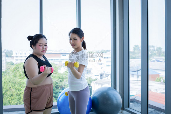 幸福合身胖的亚洲女人和教练员在健身班工作该训练员建议为肥胖妇女减锻炼体重培训员建议对肥胖妇女进行减运动图片