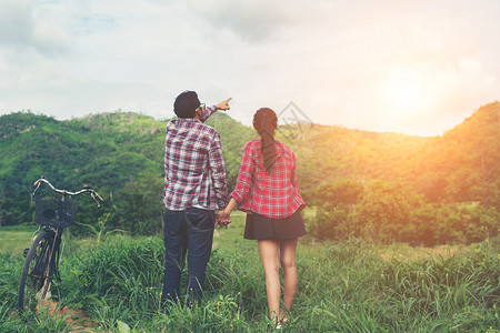 山年轻的嬉皮士夫妇手牵在草地上散步微风公园图片