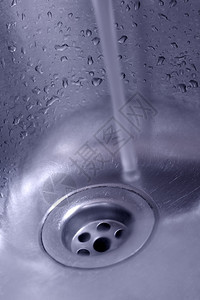 气泡从低角度拍摄的蓝色杜诺酮中含倒水的金属厨房槽现代的污图片