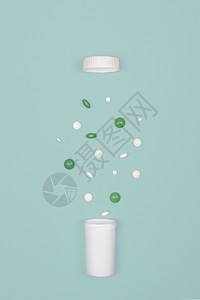 白药丸和绿从瓶子中泼出放在蓝色背景的瓶子上平板普丁概念带药丸和瓶子的医背景带有丸和瓶子的医疗背景药店品丰富多彩的图片