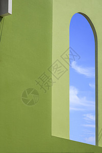 颜色角度蓝天空的侧面视角在绿色混凝土墙上的开放外窗拱形框内旧房子建筑的绿色水泥墙上泰国图片