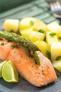 饮食海鲜垂直的烤鲑鱼片上面和右边有绿色的石灰网和煮土豆选取焦点聚于顶部和右侧的paragu头端图片