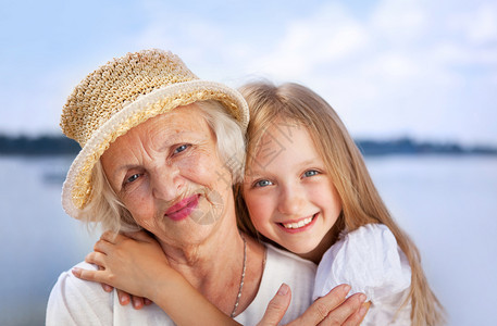 成人快乐的拥抱祖母和外孙女肖像在阳光夏日看摄影机时被拍下来晴天图片