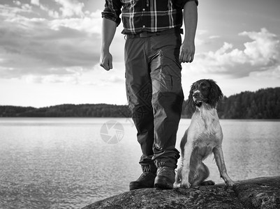黑色的婊子细心猎人和他的英国Spaniel小狗在岸上图片