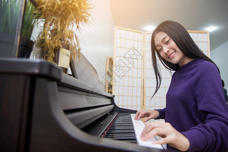 旋律经典的艺术美丽亚洲女在弹钢琴时有选择地关注面部图片