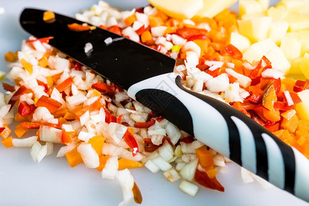 自制白色的切割板上新鲜和冷冻切碎蔬菜胡萝卜土豆洋葱和红铃椒健康图片