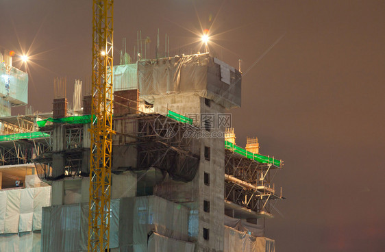 在职的轮廓工业建造起重机和夜间建筑的设城市图片