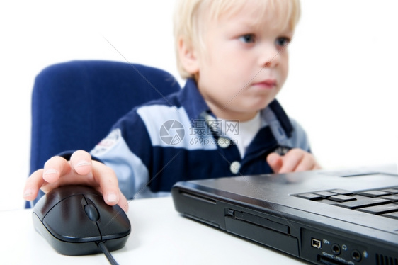 一个小男孩坐着使用笔记本电脑他可以从胸前向上看不照相机关注的焦点是笔记本电脑和鼠标水平架式专注手部和电脑鼠标金发重点陷害图片