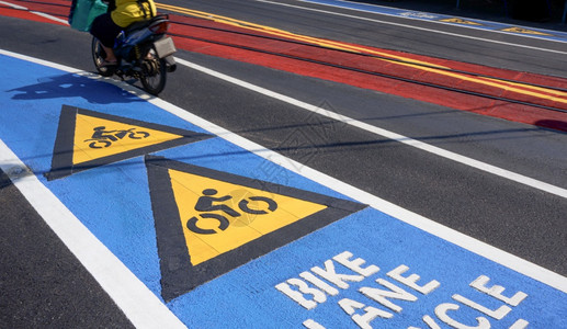 彩色自行车路标箭和自行车道文字沥青公路上摩托车的移动模糊不清街道地表交通标志和概念上有铁轨跨越的道路交通标志和象征白色的城市图片