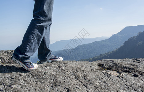 男人积极的在悬崖山顶边缘行走的人旅概念男图片