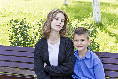 黑色的姐和哥夏天都坐在长椅上户外的姐弟微笑图片