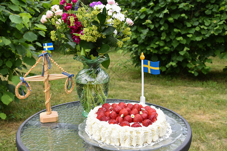 旗帜花瓶盛夏在瑞典一个绿色花园的夏初中秋桌上装饰花草莓蛋糕图片