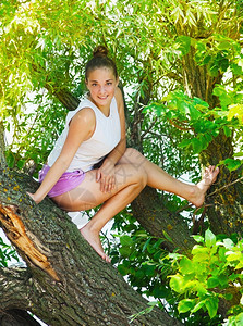 坐在夏日树上的年轻漂亮运动女孩健康绿色运动型图片