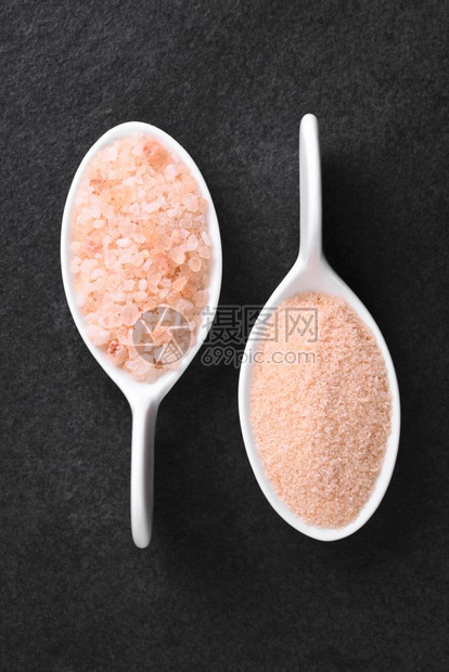 自然调味品垂直的小勺子上粉红喜马拉雅盐的粗糙和精细粉红喜马拉雅盐在板块选择焦点盐和粉红喜马拉雅盐上拍摄了头部照片图片