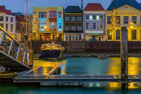 风景水荷兰热流行城市泽一艘轻光的船和建筑物从码头出发夜晚在Vlissingen市上美丽的景色黑暗图片