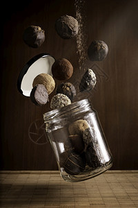 漂浮由美味的飞巧克力松露和木本面浮动玻璃罐组成的具有创意摄影作品构成在木底背景上甜的品种图片