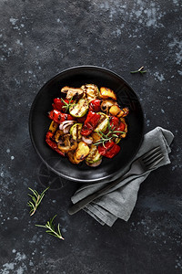 灰色蔬菜盘子里的蘑菇在黑色背景上烘烤的晚餐开胃菜图片