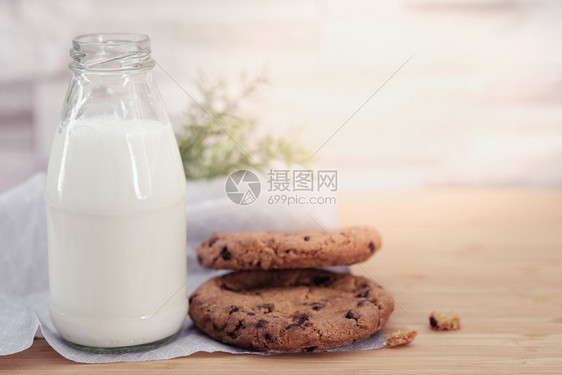 巧克力曲奇饼干和一杯牛奶在温暖的阳光下在木制桌台上乳品甜点花生图片