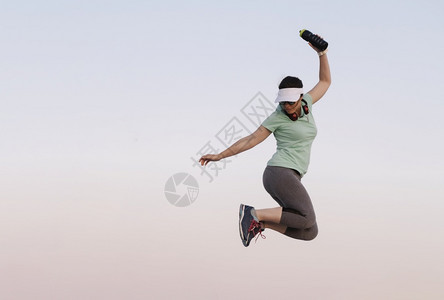 人们妇女跳跃时在蓝背景下参加运动一种合身图片
