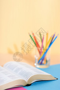 一种研究过圣经书和玻璃带有一套彩色铅笔印在纸背景上准备研究并加下划线供圣经研究补给品图片