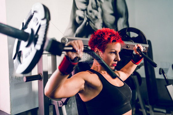 重量火车在健身训练中年轻肌肉女子运动员在健身锻炼时的体肩部按压机体减肥年轻的图片
