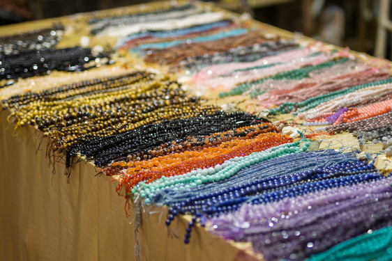 细绳配饰珠宝显示在一张表格上显示的带有彩色珠子颈项表格堆放上的带彩色珠子颈项堆积图片