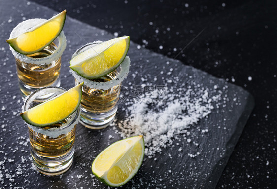 墨西哥传统喝的龙舌兰酒杯圆边和石灰上含盐的龙舌兰杯黑底酒精鸡尾墨西哥传统饮料桌子水果酒吧图片