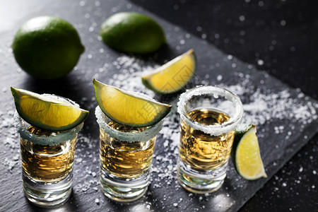 一杯含石灰的龙舌兰酒杯和洒在黑底精鸡尾墨西哥传统饮料上的盐新鲜黑暗酒吧图片