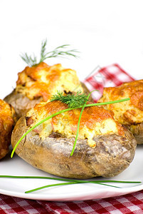 火腿糖类莴苣土豆塞满了切达干酪的土豆上面装饰着薯条和叶夹在白色板块中图片