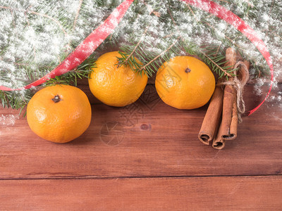 卡片普通话食物3个橘子和三根肉桂棒在fir树枝下图片