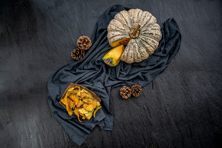 异国情调美味的烘烤黑石纹理上自制的香脆南瓜芯片和美味极了的平板布料图片