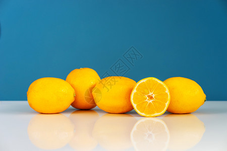 维他命在蓝色背景墙前的白桌子上黄熟柠檬切成半多汁柑橘水果新鲜实黄色的热带图片