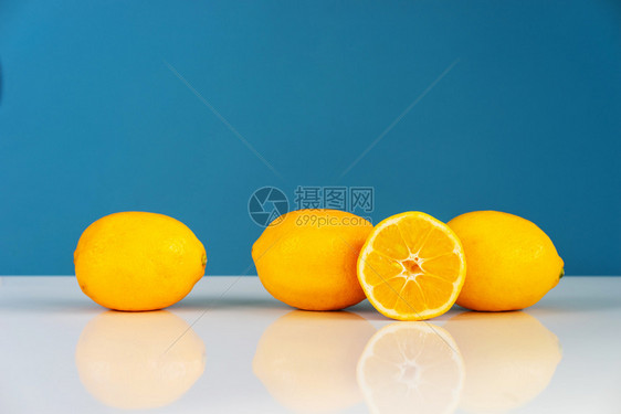 素食主义者在蓝色背景墙前的白桌子上黄熟柠檬切成半多汁柑橘水果新鲜实绿色的图片