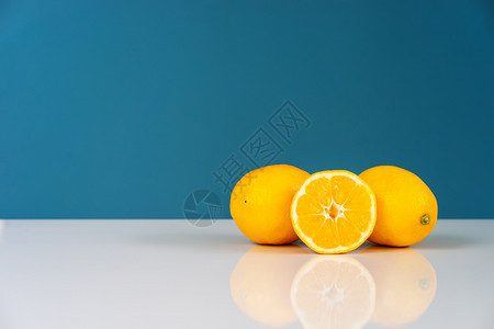 蓝色的在背景墙前的白桌子上黄熟柠檬切成半多汁柑橘水果新鲜实切碎的维他命图片
