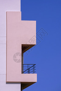 建筑学垂直框蓝天空背景的粉红面住宅楼壁上的阳台侧边视图以垂直框架为蓝天背景粉色的酒店图片