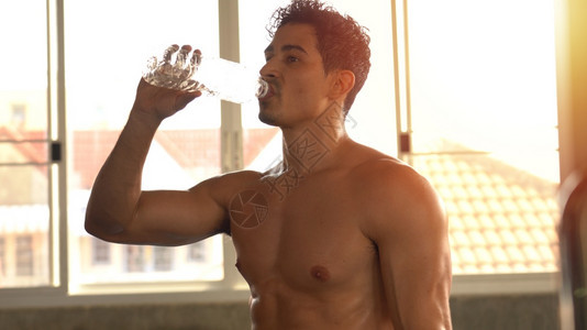 喝轻松竞技健身房的肌肉形状男人放松饮用能量料图片