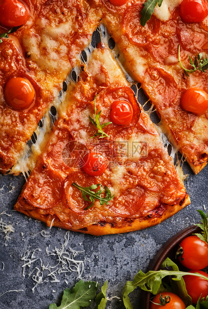 切片萨拉米小吃灰石背景上的辣椒尼比萨和樱桃西红柿切成美味的辣椒尼披萨在灰石背景上图片