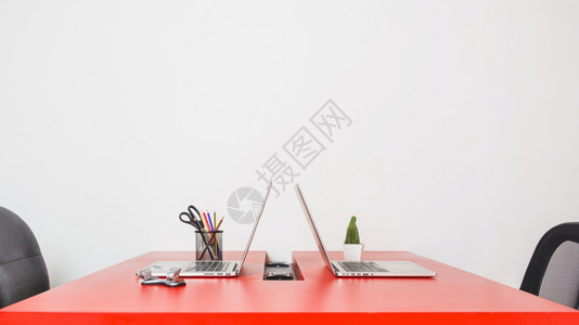 花朵高的现代工作场所与两台笔记本电脑红色桌子靠在白墙上分辨率和高品质美丽照片现代工作场所与两台笔记本电脑红色桌子靠在白墙上高品质图片