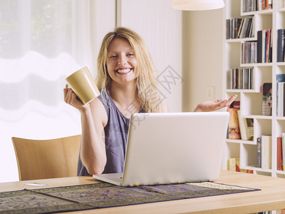 漂亮的内部一位美丽年轻女在网上购物和喝咖啡的相片笔记本电脑图片
