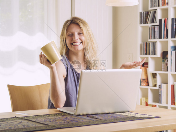 漂亮的内部一位美丽年轻女在网上购物和喝咖啡的相片笔记本电脑图片