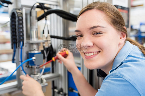 商业训练二十多岁女学徒工程师在厂机器上作的肖像在工厂中作图片