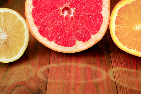 营养脆皮吃切葡萄油橙和柠檬反映在地表切割的葡萄树橙上柠檬则反映在木质表面多汁柑橘水果上图片