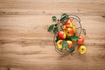 新鲜红苹果在木制桌顶视图的篮子里放叶维他命海浪生的图片