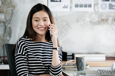 微笑在办公桌工作和讲电话的年轻亚洲女商业人余休闲生活方式和在办公桌工作并通电话的忙碌行政人员图片