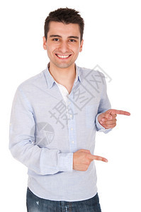 手势衬衫微笑着的年轻临时男子指着白色背景上孤立的东西指着青年图片