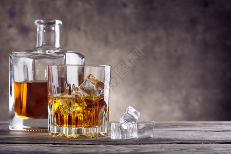 威士忌和冰立方在木制桌边的冰立方威士忌和冰立方颜色苏格兰人黄的图片