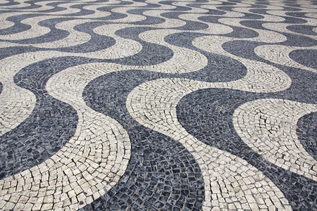葡萄牙语波浪状的铺砌葡萄牙里斯本典型的葡萄牙鹅卵石手工路面图片