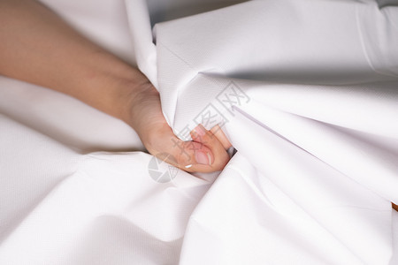 妇女用手挤住床单颜色是白的材料在下面紧张图片