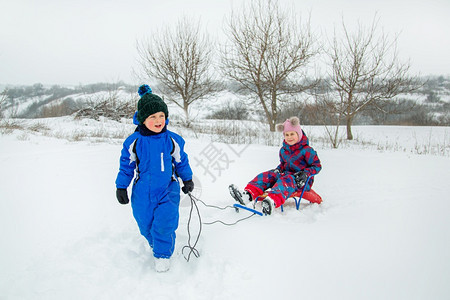 闲暇男生快乐的孩和女在冬天从山上拉雪橇冬季户外运动会寒假快乐的男孩和女在冬天从山上拉雪橇冬季户外运动会兄弟图片