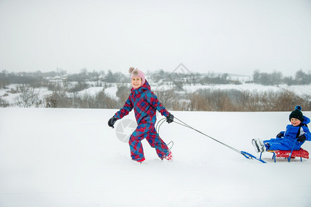 快乐的男孩和女在冬天从山上拉雪橇冬季户外运动会寒假冬季户外运动会公园冷冻周末图片